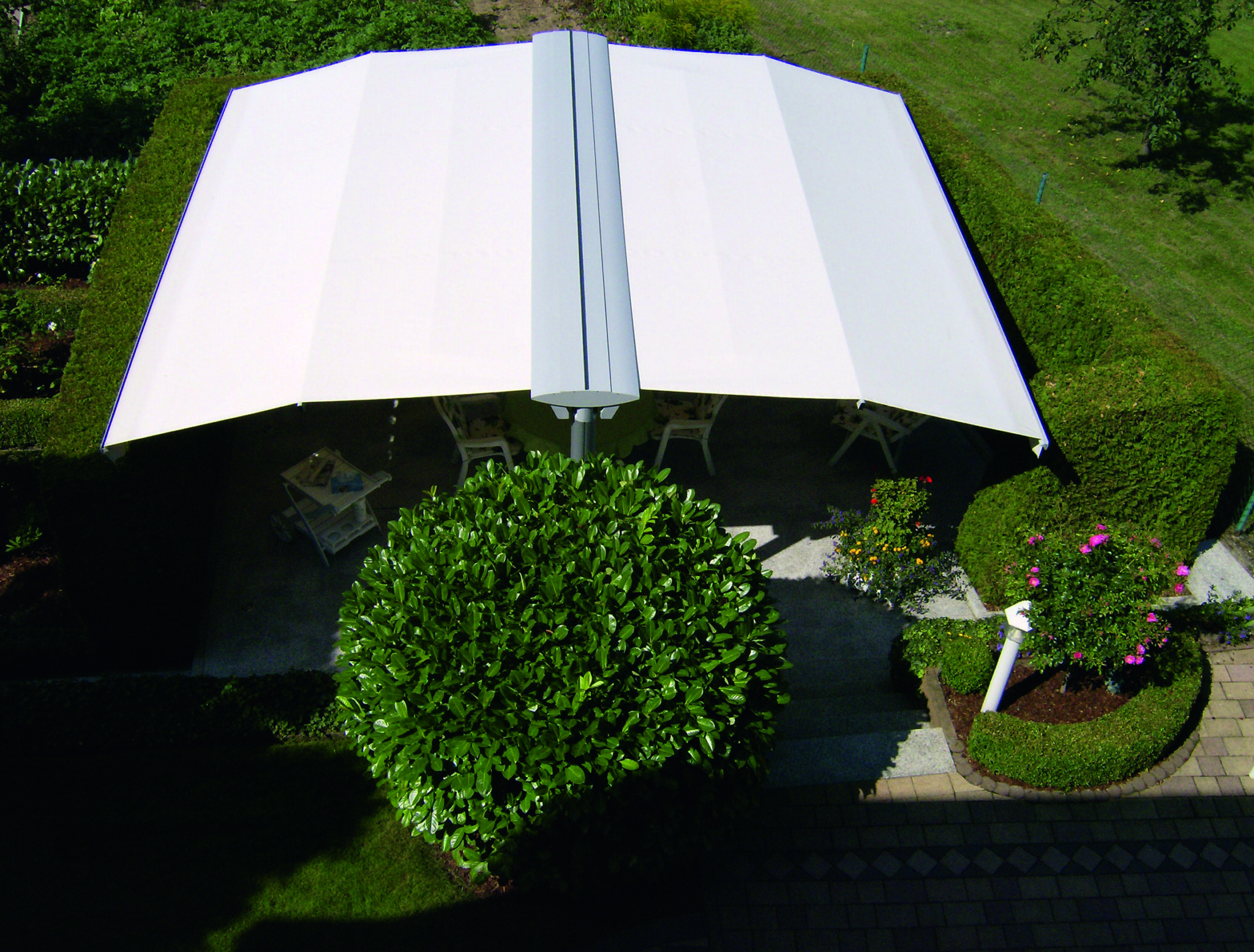 Außenbereich eines Restaurants mit flächigen Sonnenschirmen Bild von oben von einer freistehenden Markise mit weißem Tuch