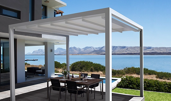 Freistehende Pergola mit Sitzgelegenheit darunter und Bergen und See im Hintergrund.