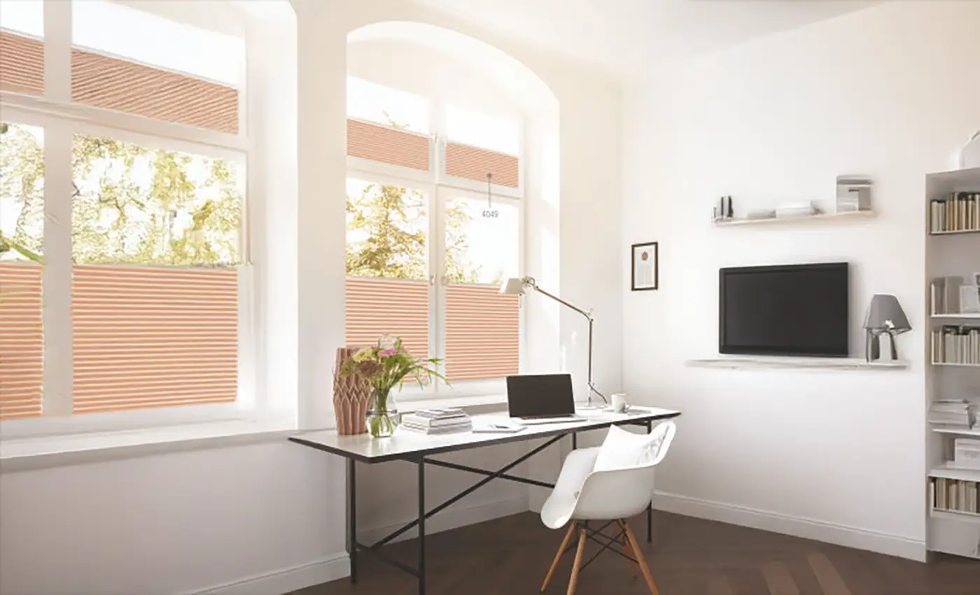 Ein helles Büro mit pfirsichfarbenen Plissees